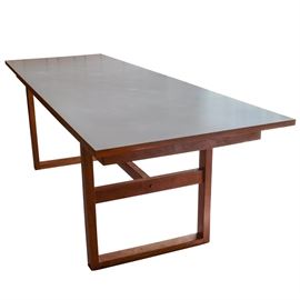 Mid-Century Modern Dining Table by Otmar: A mid-century modern dining table crafted by Otmar. The table has an affixed white laminate top with a trestle base and center stretcher.