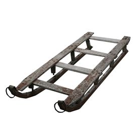 Antique Red Painted Wood and Iron Sled: An antique red painted wood and iron sled. This freight sled features wrought iron wrapped runners with large rings to the front, pegged construction, and an old red paint finish. The piece is unmarked.
