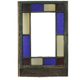 Vintage Stained Glass Window: A vintage stained glass window. This window features alternating stained glass panes, with square red corners and blue and colorless panes in between. One side exhibits an old dark green paint while the other is in white. The piece is unmarked.
