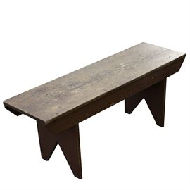 Pine Bench in Old Red Paint: A pine bench in old red paint. This early pine wood bench features a single board top with angle-arched feet and trapezoidal aprons. The latter two features both still exhibit an old red paint finish.