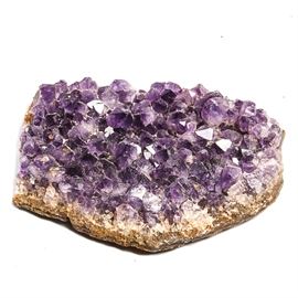 Amethyst Geode: An amethyst geode. This geode features crystals in various shades of purple. The outer part of the crystal is a stone in various shades of brown and gray.