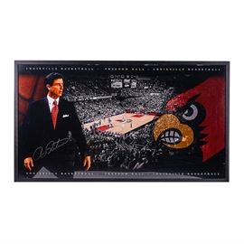 Rick Pitino Signed Louisville Cardinal's Freedom Hall Poster: A University of Louisville basketball poster signed by Rick Pitino. The poster has an image of the Cardinals playing a game in Freedom Hall, with the school mascot to the right and an image of Pitino, U of L basketball coach since 2001, to the left. Pitino has signed in silver-tone ink across his dark suit. It is framed, with wire in back for hanging.
