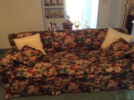 Sofa with sofa table behind it - collectible items on sofa table and built in bookshelf with additional collectibles. 