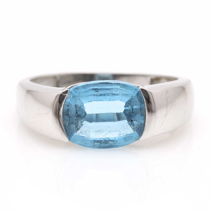 18K White Gold Topaz Ring: An 18K white gold topaz ring. This ring features a smooth shank leading to a half bezel set blue topaz stone.