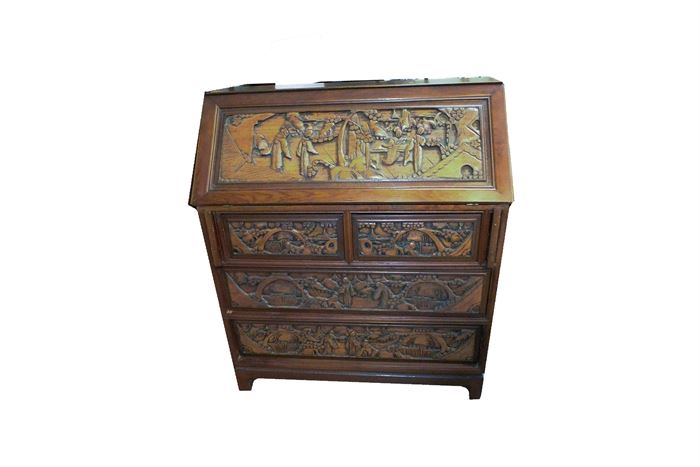 Carved Asian Secretary Desk: A carved Asian secretary desk. The desk features four drawers beneath a secretary style folding desk. The desk portion has sections for papers within. The piece features scenes of Asian antiquity carved throughout.