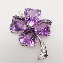 14K White Gold Amethyst Four-Leaf Clover Brooch/Pendant: A 14K white gold amethyst and diamond four-leaf clover brooch/pendant. This brooch features four amethyst heart-shaped stones with a diamond center and diamond embellished stem. It includes a purple box.