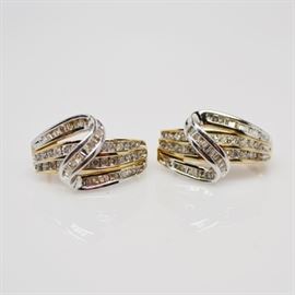 10K Yellow and White Gold Diamond Pierced Earrings: A pair of 10K yellow and white gold diamond pierced earrings. These channel set diamond encrusted earrings feature round brilliant cut diamonds set in two rows of yellow gold, and baguette diamonds in a curving ribbon of white gold.