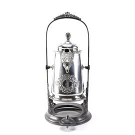 Pairpoint Manufacturing Company Silver Plate Tea Kettle: A silver plate tea kettle. This antique kettle is made by Pairpoint Manufacturing Company, it is marked to the bottom “Quadruple Plate.” The kettle is removable from the stand and both pieces of the set feature a floral design.