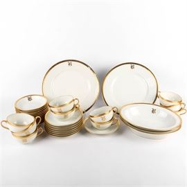 Theodore Haviland Limoges China Set: A selection of Theodore Haviland Limoges china. The collection includes two dinner plates, two oval serving bowls, eight saucers, twelve berry bowls, and ten cups. Each piece has an ivory colored body with a gold tone rim. All pieces with the exception of the saucers are monogrammed with the letter “B” in a gothic style type. All pieces are marked “Theodore Havilland Limoges France” to the underside.