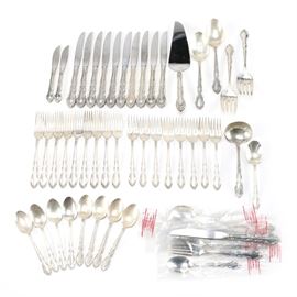 Oneida Sterling Silver "Grandeur" Flatware: A collection of Oneida sterling silver flatware. This grouping includes two hollow handle master spreaders, approximately twelve hollow handle knives, one hollow handle pie server, one flat handle pierced tablespoon, one flat handle serving spoon, two flat handle serving forks, approximately eleven flat handle dinner forks, approximately eleven flat handle salad forks, one flat handle ladle, one flat handle sugar spoon, and approximately eleven teaspoons. These pieces feature the Grandeur pattern to the handles. Each utensil is marked “Heirloom Sterling by Oneida” and the total approximate weight is 51.135 ozt.