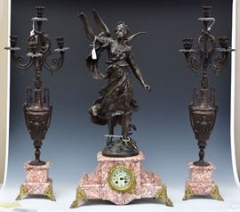 French Three Piece Clock Set	
Clock with Classical Figure with Wings
31 3/4" high, together with a pair of
four light candelabra with female masks,
each 32 1/2" high
rouge marble with bronzed white metal
early 20th century