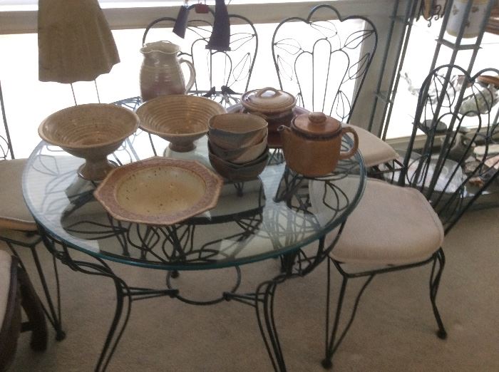 Glass top wrought iron cafe table and four chairs, signed pottery pieces
