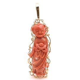 Carved Coral Buddha With 14K Yellow Gold Findings: A carved coral Buddha with 14K yellow gold findings. This item features a traditional bail with wrapped wire encasing a Buddha holding an alms bowl.