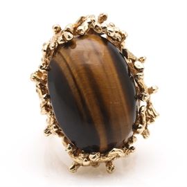 14K Yellow Gold Tiger's Eye Ring: A 14K yellow gold tiger’s eye ring. This ring features a decorative branch styled shank leading to a decorative pierced gallery housing a prong set tiger’s eye stone.