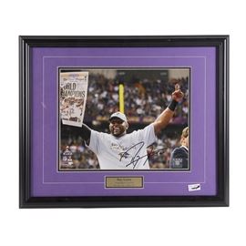 Ray Lewis Signed NFL Super Bowl XLVII Framed Photograph: A Ray Lewis signed NFL photographic print titled “Super Bowl XLVII”. This piece depicts the retired Baltimore Ravens linebacker on the field with a champions shirt and newspaper. It is signed in black pen by the player along with his number 52. Presented double matted under plexiglass with a plaque in a black frame wired to verso for hanging.