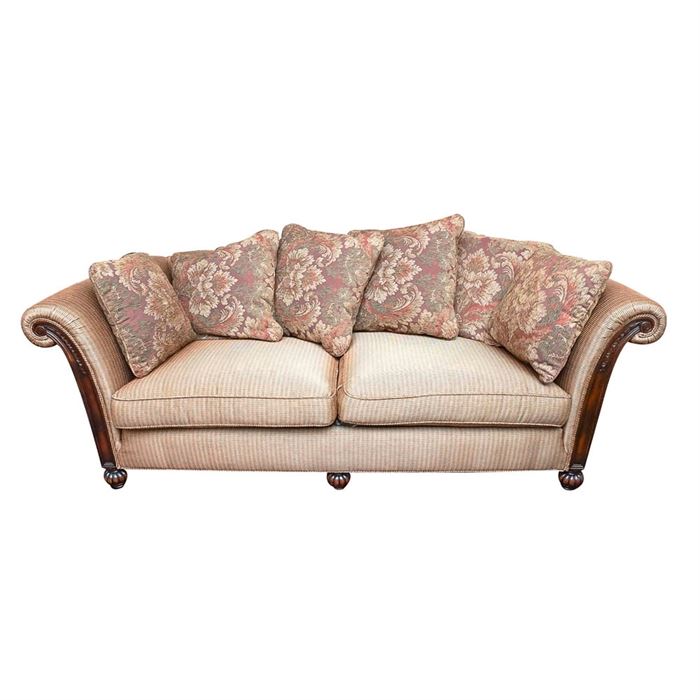 Wood Frame Upholstered Sofa with Accent Pillows: A large sofa with a high back and sides, manufactured by Sherrill Furniture, this piece features a dark brown carved wooden frame with turned bun feet. The fabric of the sofa had silver, gold red, and green colors in small rectangular shapes on it. There are two large seat cushions on the bottom. The sofa comes with six matching accent pillows covered in a floral design with red, green and gold colors.