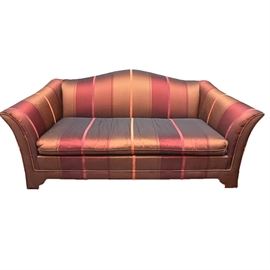 Chippendale Style Camel Back Sofa: A Chippendale style camelback sofa. The settee features a removable cushion and a striped upholstery with shades of red and gold. There are no tags present on the sofa.