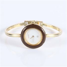 Gucci Women's Bangle Wristwatch: A Gucci women’s bangle wristwatch with a cream dial and a brown stone bezel.