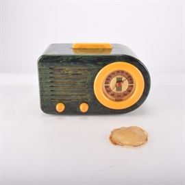 Vintage FADA Bakelite Radio: A vintage FADA 115 ‘Bullet’ Catalin radio in a Bakelite case. The case is a marbled green with yellow accent handle, knobs and face edging. One side is straight and the other is rounded in an Art Deco design.