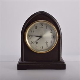 Seth Thomas Vintage Gothic Mantel Clock: A Seth Thomas mantel clock. The beehive clock features a dark stained wood case with brass tone bezel with glass front door that open to a metal analog clock face marked “SF”. The back features a hinged door with a knob handle that opens to reveal the interior brass tone gears with wind-up key set on a rounded beveled base.