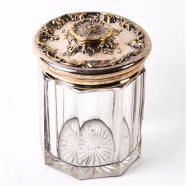 Victorian Silverplate and Glass Jar: A Victorian glass jar with a silverplate lid. The jar is paneled and the lid features scrolling foliate embellishments. Item is unmarked.