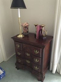 French horn book ends, brass lamp atop a small, three-drawer end bureau.