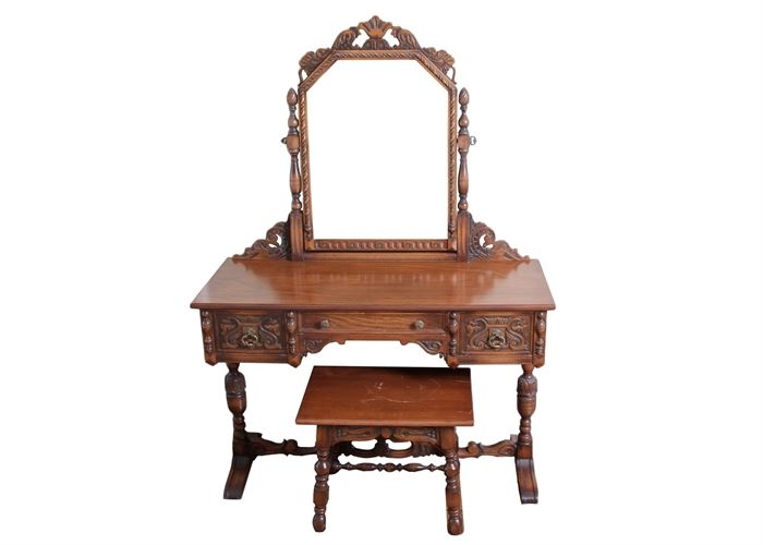 Antique Wooden Vanity and Stool: An antique wooden vanity and stool. This vanity and stool has intricate carvings. It has three drawers across the front of the vanity and a removable mirror at the back. The small stool has a matching design.