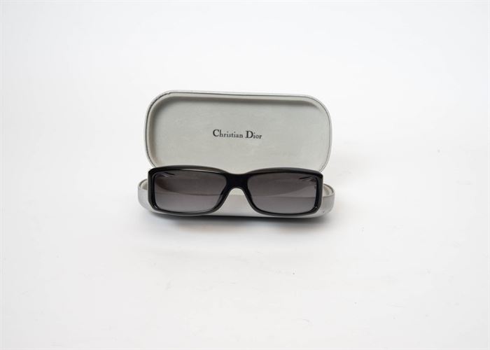 Christian Dior Sunglasses: A pair of Christian Dior sunglasses. This pair of sunglasses have black rims and come in a silver-toned case. The case is marked “Christian Dior”. The glasses are engraved on one temple arm with “made in Italy DiorCelebrity4 885 57 14 125”.