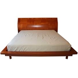 ALF Italia King Size Bed Frame: An ALF Italia contemporary style king size bed. The bed features a tall curved panel headboard and a rounded platform base. The bed features a high gloss finish to the wood veneers and rests on four straight legs.
