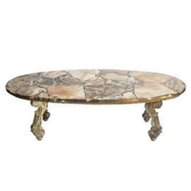 Agate Coffee Table: An oval shaped coffee table with an agate slice top. The piece rests on four acanthus leaf scrolled legs with a gold tone finish.