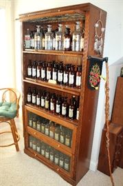 Leaded glass barrister bookcase with collection of Wyeth pharmacy bottles