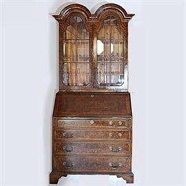 Antique Georgian Style Double Arched Cornice Walnut Secretary: An antique Georgian style burl walnut double arched cornice secretary bookcase, circa 1900. The upper section designed with a dimensional double arched cornice, double doors with trefoil arched glass inserts accented with muntin trim, with a pair of pull-out candle slides below, and to the interior, two adjustable wood shelves. The back of the bookcase is in a pine board construction. The base features an arrangement of four gradated dove-tailed burl-fronted drawers with brass bale pulls and contrasting inlaid borders, and above a slant front writing cabinet outfitted to the inside with nine open cubbies and nine small burl-fronted drawers, with four in a curved form. The bookcase is finished with French bracket feet and beveled trim, and flat panel sides.