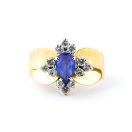 14K Yellow Gold, Tanzanite, and Diamond Ring: A 14k yellow gold, Tanzanite, and diamond ring. It features a pear faceted tanzanite center stone and clusters of round brilliant cut natural diamond side stones on a golden band.