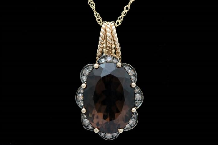 14K Gold, Smoky Quartz and Diamond Pendant with Chain: A 14K gold, smoky quartz and diamond pendant with chain. The pendant features an oval smoky quartz surrounded by a scalloped detail accented with two sizes of brown diamonds. The pendant measures approximately 0.50" x 0.95, inclusive of bail. Included is an 18" 14K yellow gold cable chain with a spring ring clasp.