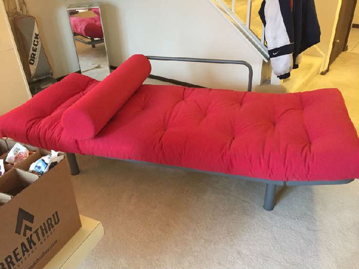 Red single futon opens to sleep and folds to couch