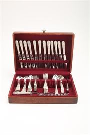 Kirk "Repousse" Sterling Flatware: A sterling silver flatware service by S. Kirk & Sons housed in a wooden chest.The service is decorated in the popular Repousse pattern first issued in1828 and consisting highly embossed floral decoration. The set is comprised of twelve knives with sterling holloware handles and stainless steel blades together with seven bouillon spoons, five table spoons, twelve teaspoons, twelve salad forks, and twelve dinner forks. The group also includes a butter knife, two serving spoons, and two ladles. There is a carving set composed of a knife and fork with a stainless blade as well as a cheese slicer also having a stainless component. There are marks impressed on the flatware reading " S Kirk & Son Sterling" and the pieces with stainless steel were produced during the Steiff period of the factory beginning in 1983. The total approximate weight is 71.65 ozt excluding the pieces with stainless steel handles.