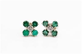 14K White Gold Emerald and Diamond Earrings: A pair of white gold earrings with prong set round cut diamonds to he center of four round cut emeralds to each.