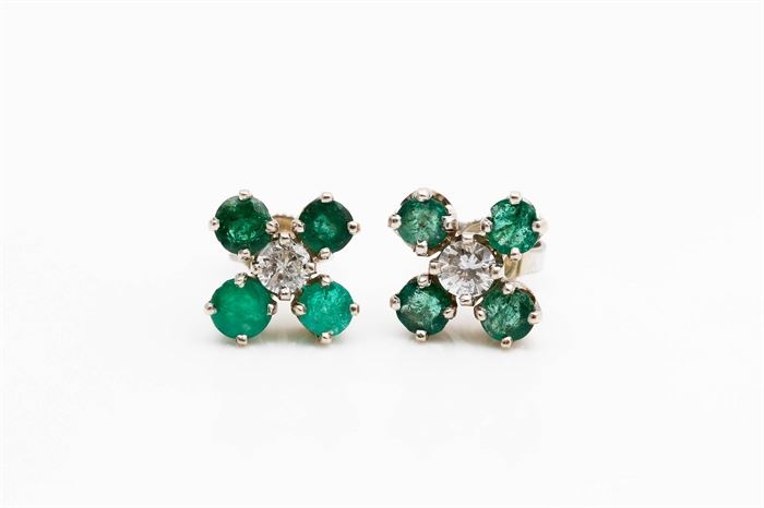 14K White Gold Emerald and Diamond Earrings: A pair of white gold earrings with prong set round cut diamonds to he center of four round cut emeralds to each.