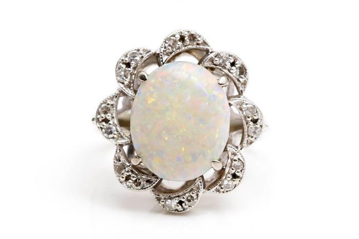 14K White Gold Opal and Diamond Ring: A white oval cabochon opal is prong set to the center of a scalloped white gold halo accented by round cut prong set diamonds.