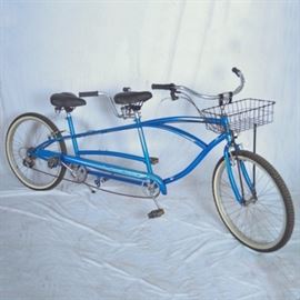 Sun Cruiser Tandem Bicycle: A Sun Cruiser tandem bicycle. This blue tandem bicycle features seven gears and front and rear caliper rim brakes. The bicycle is marked “Sun cruiser tandem” to the chain guard and has the Sun bicycles logo to the front.