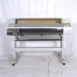 Epson Stylus Pro9600 Ultra Chrome Poster Printer: An Epson Stylus Pro9600 Ultra Chrome poster printer. This printer has a 44.0" printing area and uses the Epson UltraChrome seven-ink technology with a printer head that moves horizontally. The machine is rectangular and stands on two legs with two wheeled feet.