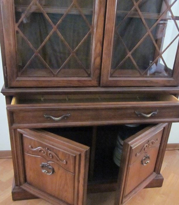 Dark oak china cabinet with brass hardware, wood fretwork on glass doors, glass shelves and sides, lighted, 1 drawer, double door storage area with shelves.  42" W, 16" D, 76" T