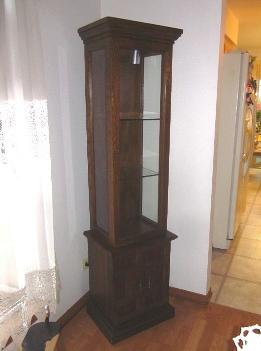 Wood curio cabinet, lighted, with glass door, sides and shelves, brass hardware and enclosed bottom storage area.  68" tall, 18" wide, 14" deep.