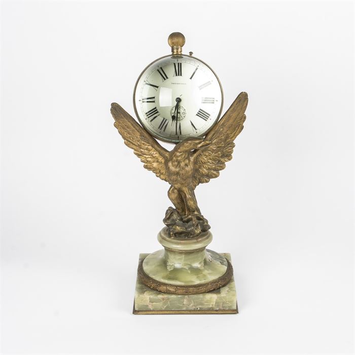 Vintage Tiffany & Co. Pedestal Clock: A vintage Tiffany & Co. mantle clock. This circa 1900’s mechanical mantle clock has black roman numerals on a white face and includes a minute sub-dial. The clock rests on an eagle’s spread wings and the eagle stands on a green onyx and gilt-bronze base. It bears the Tiffany & Co. maker’s mark to the center of the clock face.