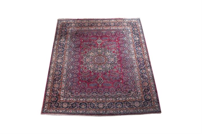 Red and Navy Kashan Area Rug: A machine made Kashan area rug. This Persian inspired rug features a palette of ruby reds, blues peaches, and beige. The field has a palette of dark navy, wedgwood blue, and pink. It has a main border with a background of navy blue with floral pink and light blue accents and a sewn-on beige fringe.