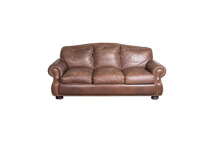 Hancock & Moore Leather Sofa: A Hancock & Moore leather sofa. This brown leather sofa has a curved back accentuated with brass-tone nail heads, loose back cushions, panel arms with nailhead trim and removable loose seat cushions with velcro attachment. It sits on bun feet. Companion to 17BAL039-003 Hancock & Moore Leather Armchair and Ottoman and 17BAL039-004 Hancock & Moore Leather Armchair and Ottoman.