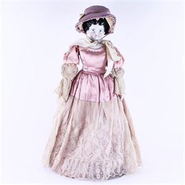 Antique "Mary Todd" China Doll: An antique “Mary Todd” china doll. The doll is dressed in a hand-stitched pink satin dress with lace, a hat, pantaloons, and an eyelet lace underskirt, with kid leather boots embellished with blue beads. The doll’s head and shoulders are hand-painted china; her limbs and body appear to be cloth. There is no mark for a maker.