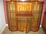 English secretary with center doors open, bowed sides with fitted glass shelves. Circe 1920.