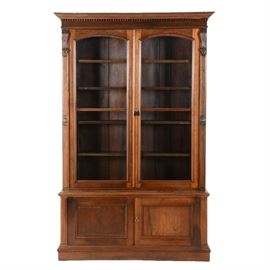 Large Walnut Display Cabinet: A circa early 20th century vintage large display cabinet in walnut. It features crown molding, carved accents, double doors with glass panes, four adjustable/removable shelves, and a lower cabinet space with solid double doors. Unmarked.