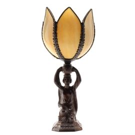 Vintage Art Deco Style Lamp: A vintage Art Deco style lamp. This lamp is cast iron with a bronze-tone finish depicting a kneeling woman with an urn on her head. The lamp shade is a tulip shaped glass with a decorative frame filigree. It was tested and worked at the time of cataloging.